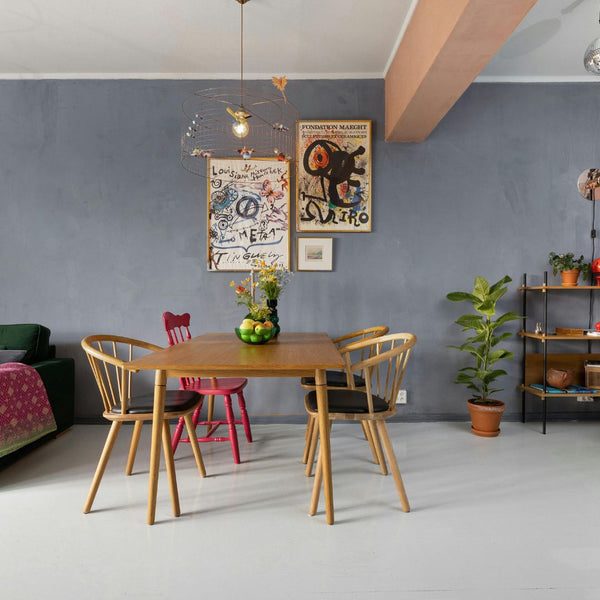 Dining area with wooden table and chairs against a gray wall with decorative posters.
