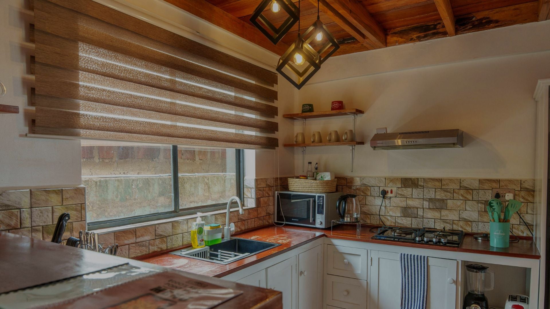 Kitchen with wooden ceiling, large window with blinds, and various appliances.